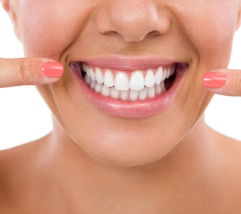 Dientes perfectos en poco tiempo con la ortodoncia rápida en Bogotá Ortodoncia rápida en Bogotá, mujer señala con sus dedos los dientes